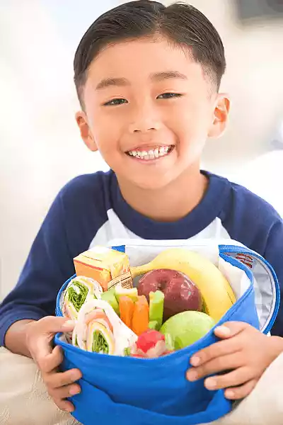 Little boy holding a lunch box packed with a healthy school lunch