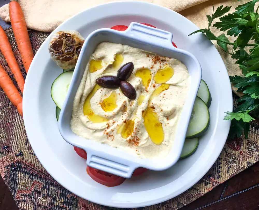 Roasted garlic hummus recipe made and in a bowl drizzled with olive oil and kalamata olives