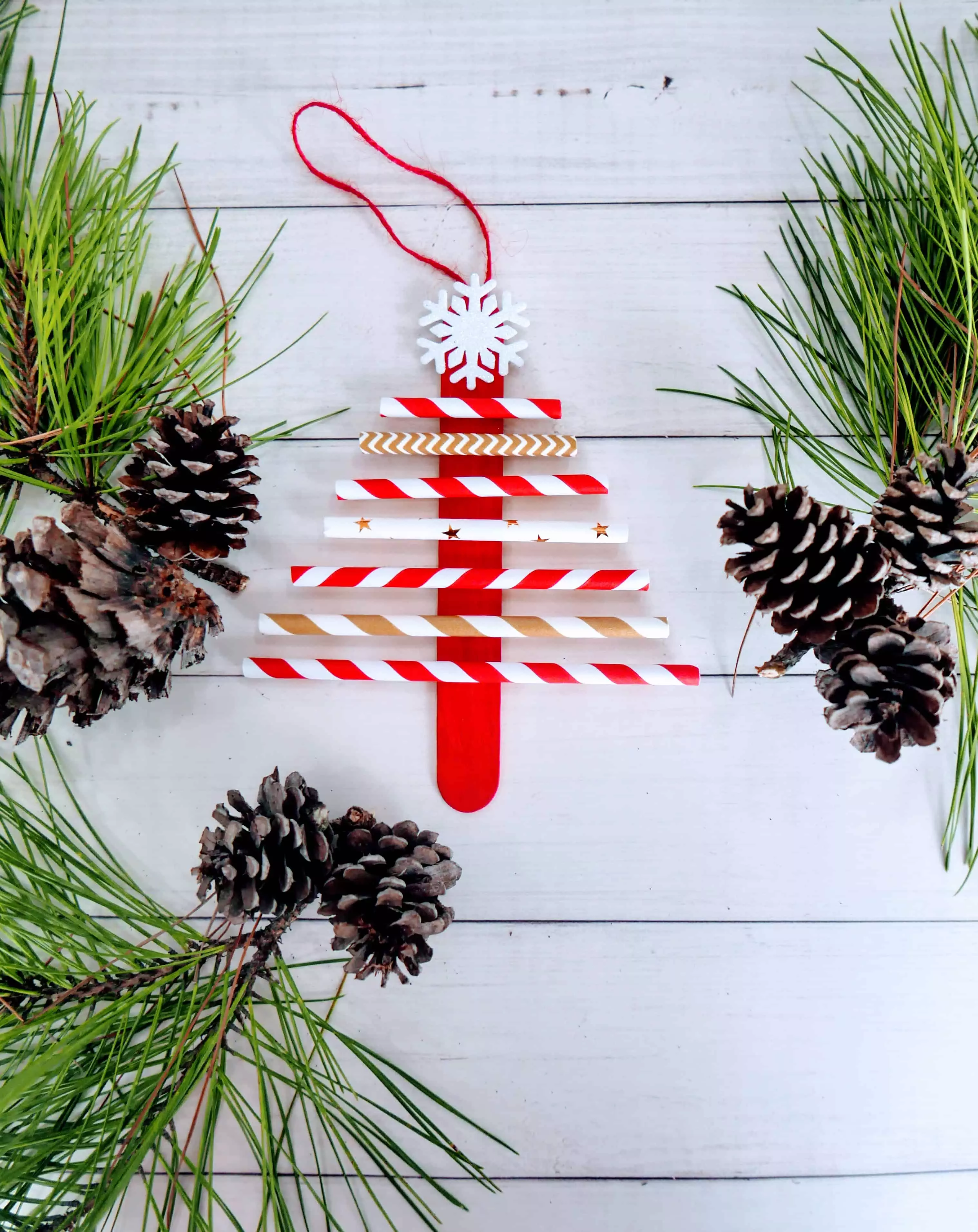 paper straw Christmas tree craft on a table with greenery