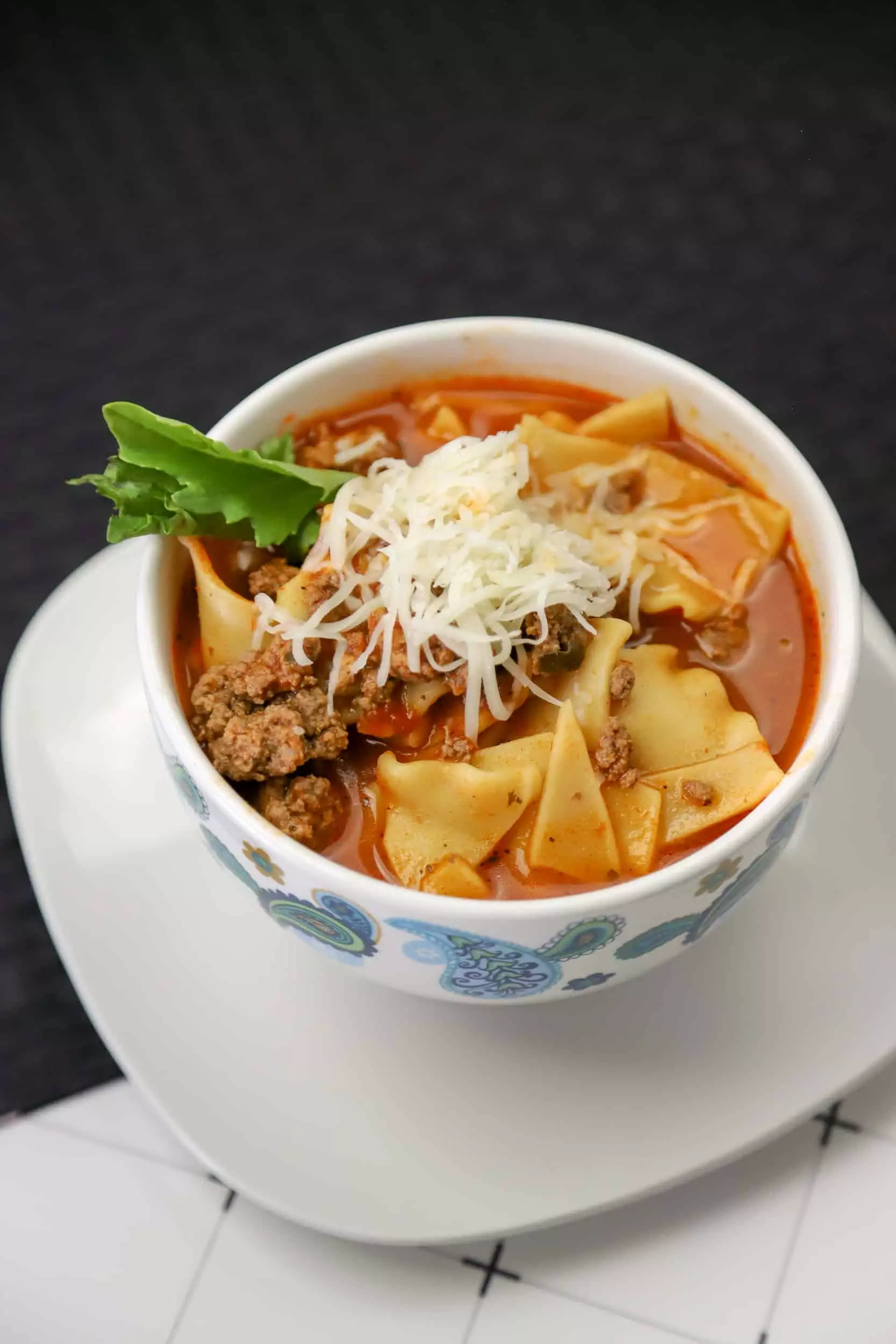Lasagna soup made in the instant pot in a bowl with a spoon and a side salad