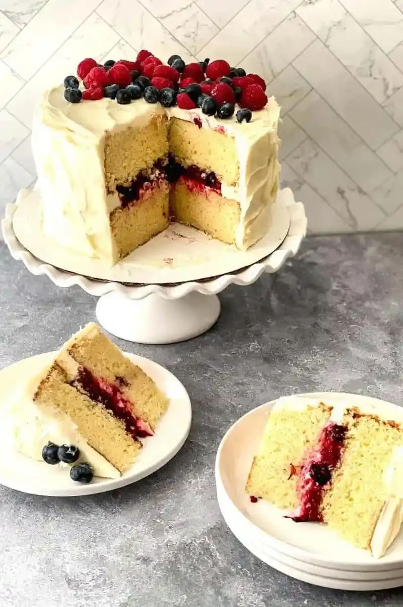 berry Chantilly cake on platter with slices on plates