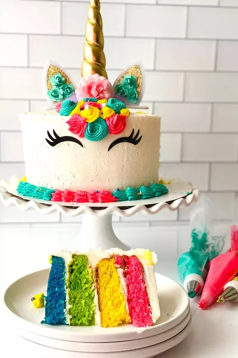 Rainbow unicorn cake with a cut slice on a plate