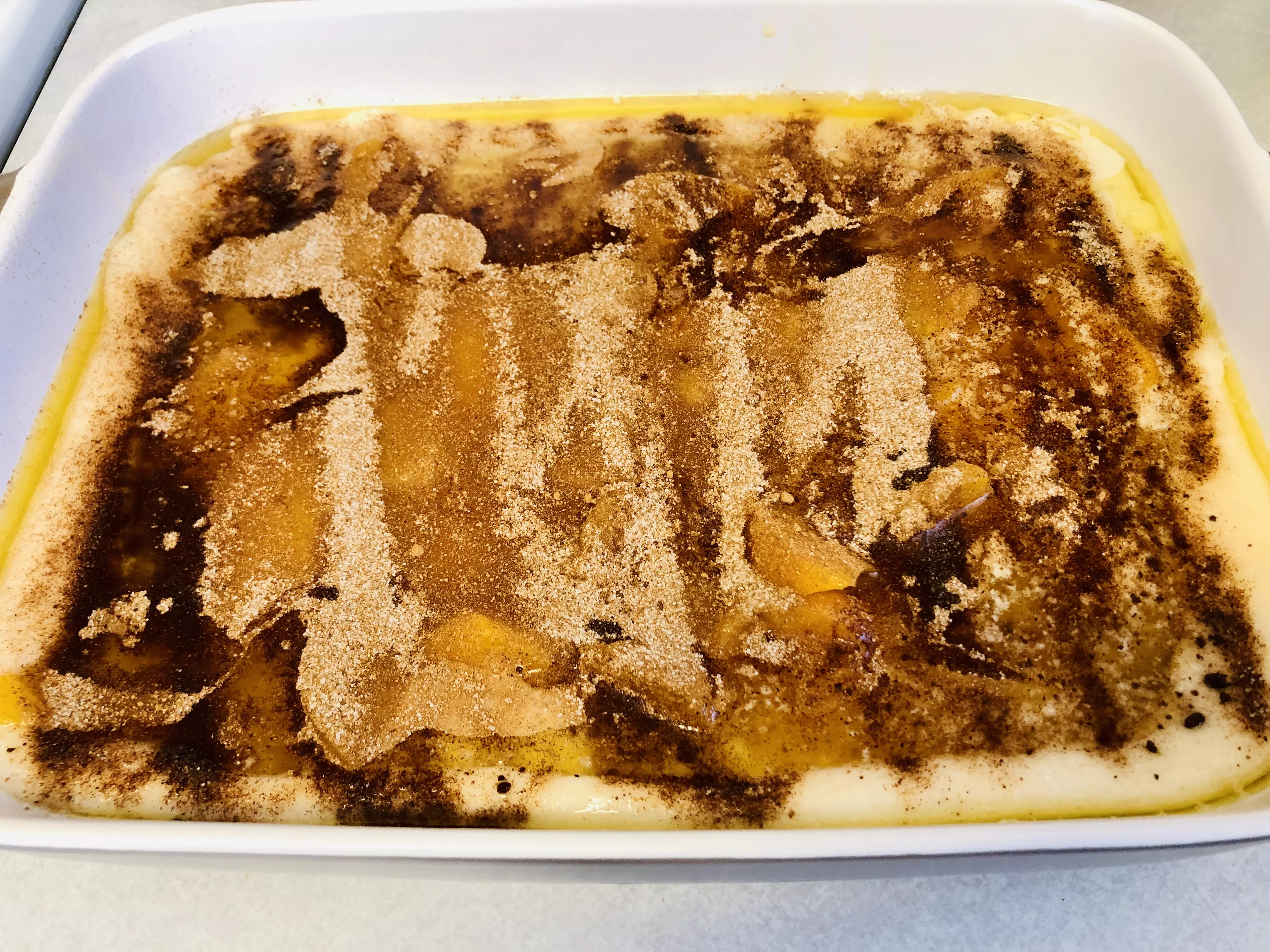 adding cinnamon and nutmeg topping to peach cobbler