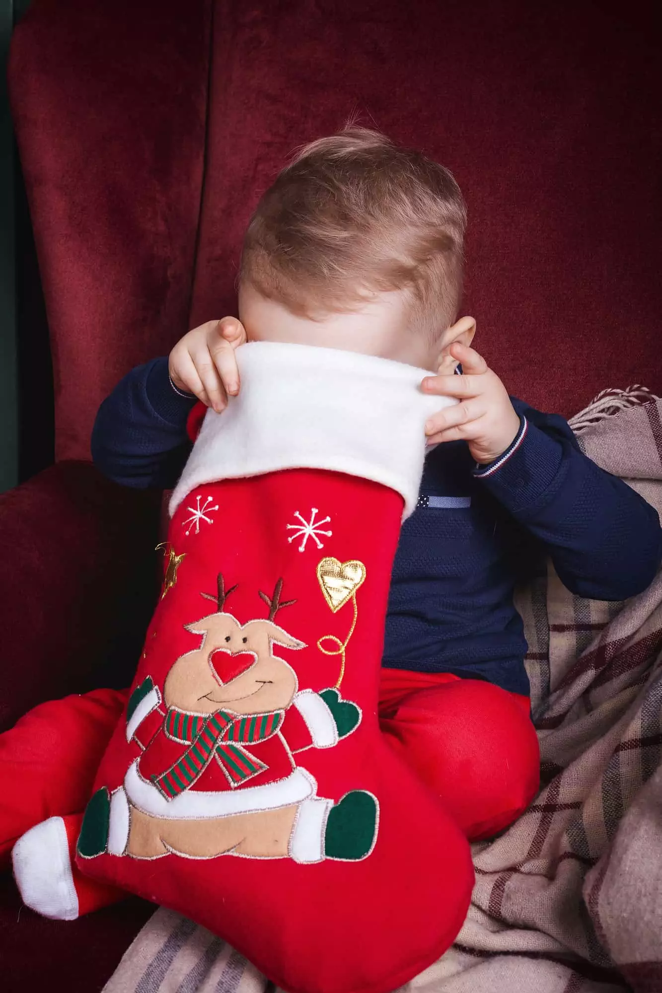 Toddler boy looking into his Christmas stocking for one of the top toddler stocking fillers ideas on this list.