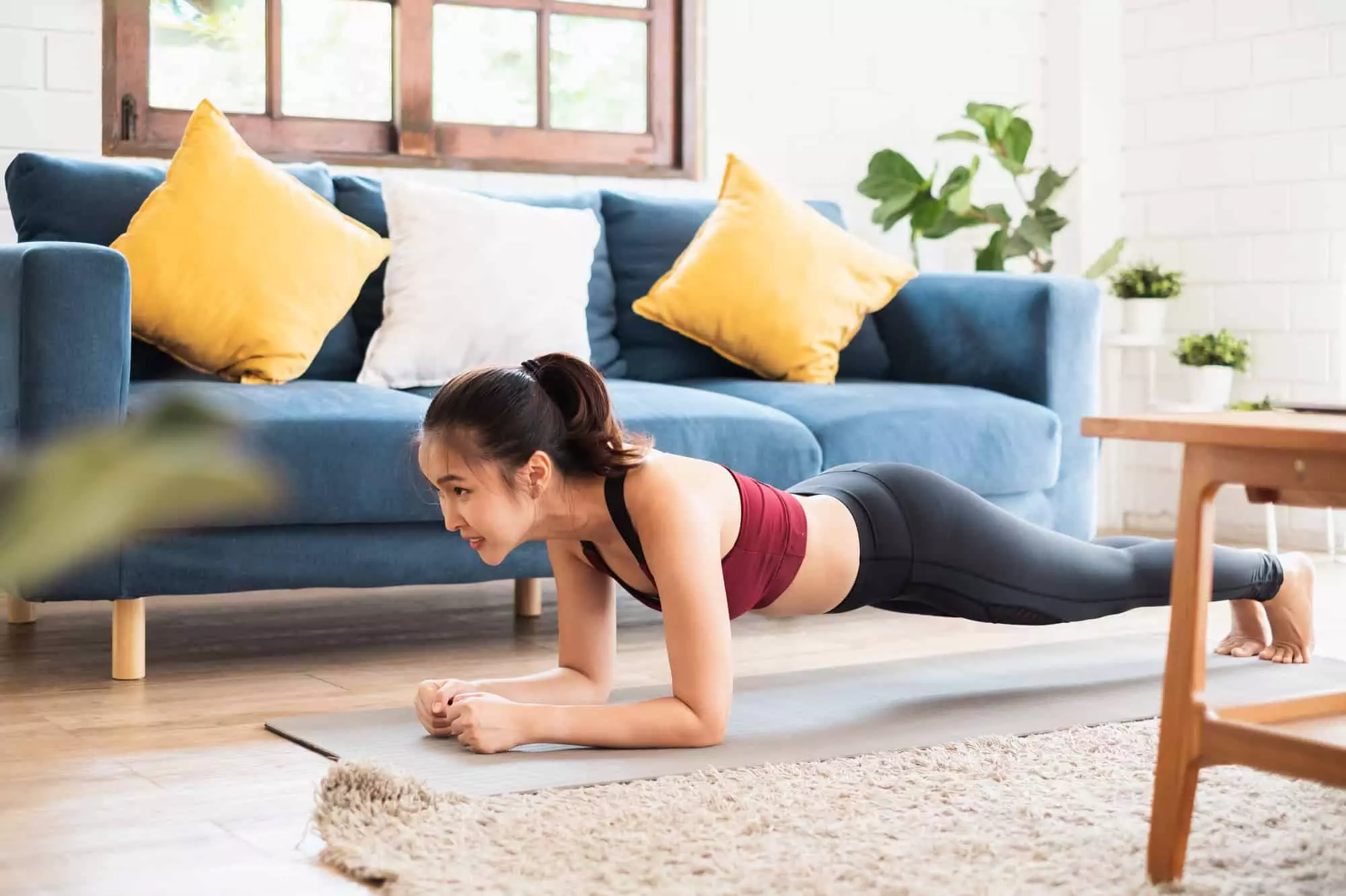 young woman doing a plank in her living room