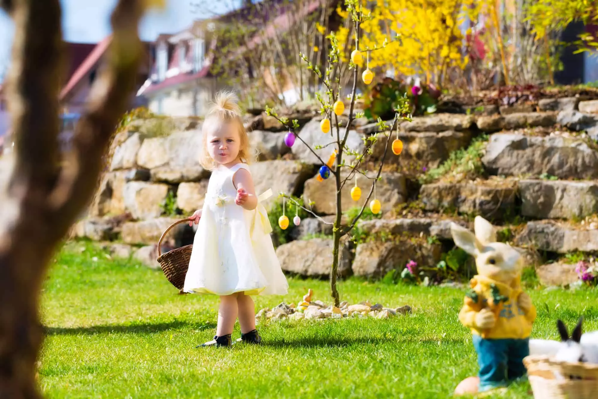 Little Girl on an Easter Egg scavenger hunt on a meadow in spring, she holding a basket or Easter basket