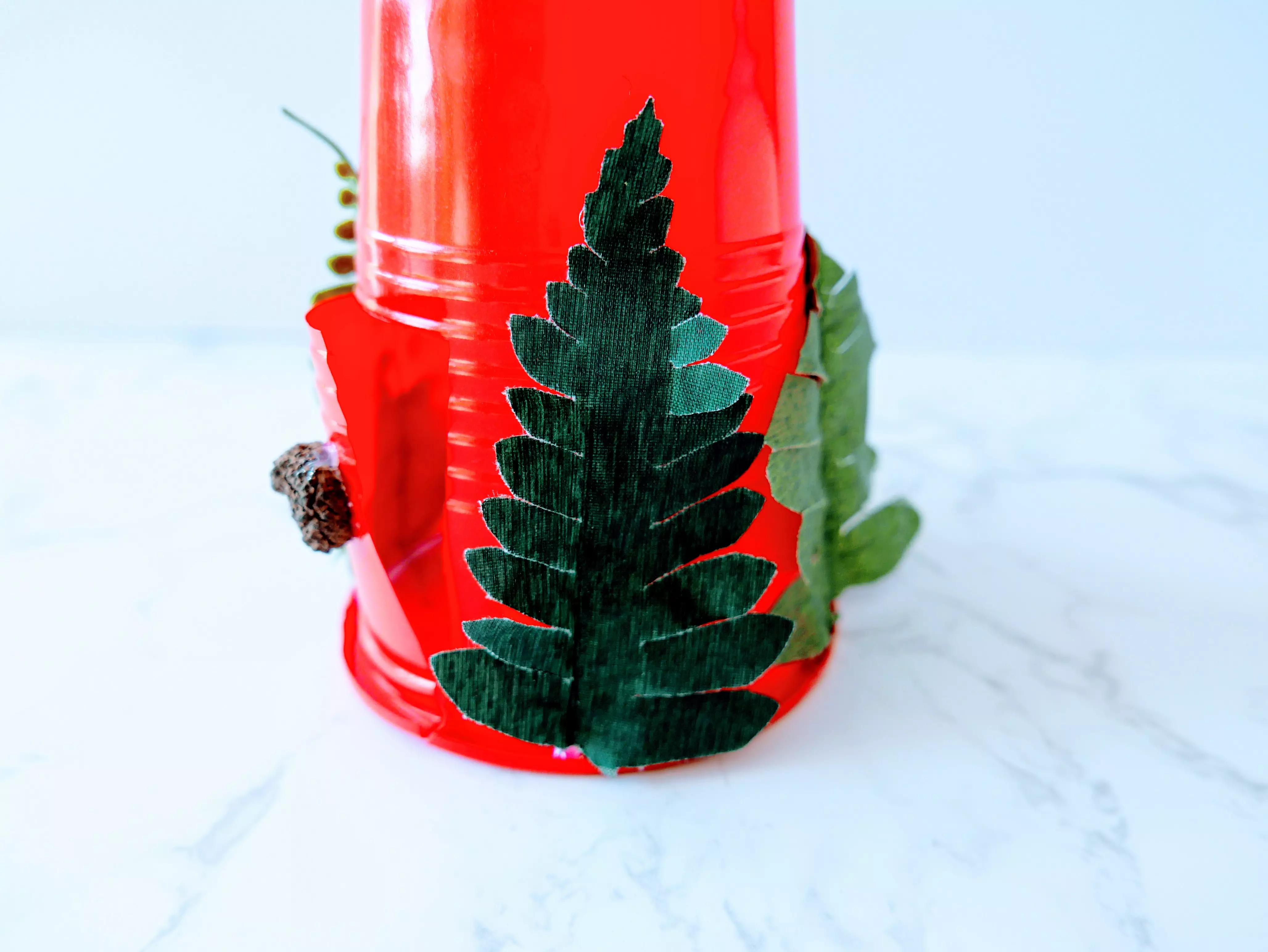 gluing greenery to a plastic cup
