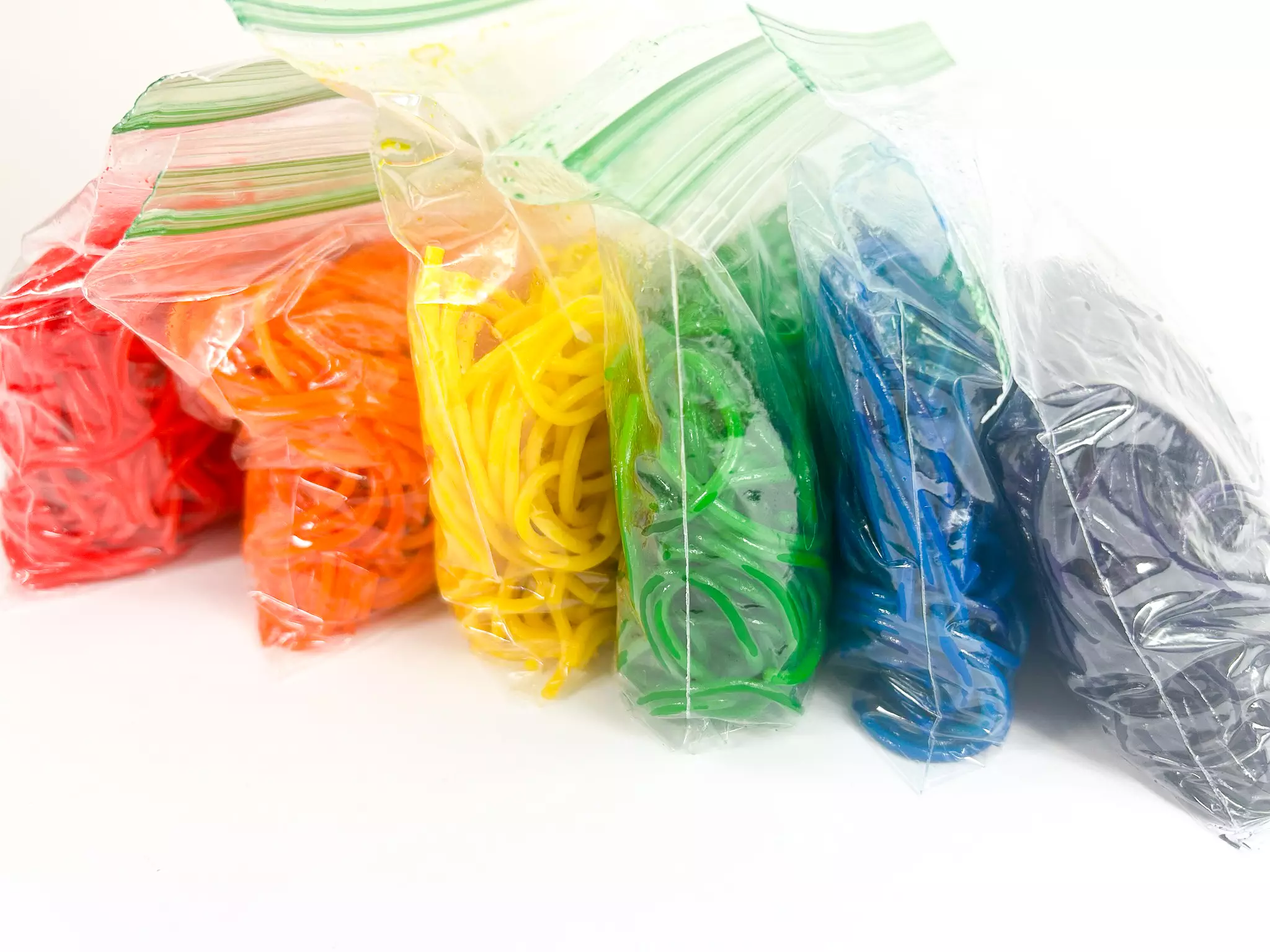 rainbow spaghetti noodles in plastic bags