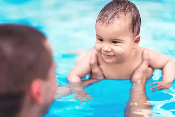 parent holding their infant in a swimming pool