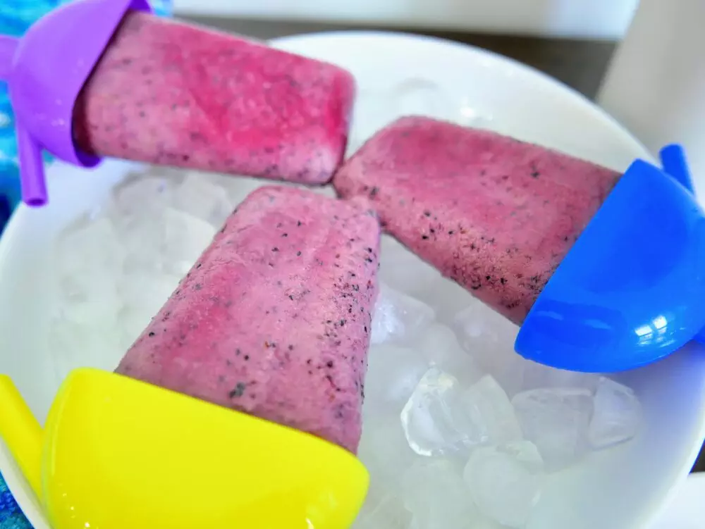 close up of 3 blueberry popsicles on ice