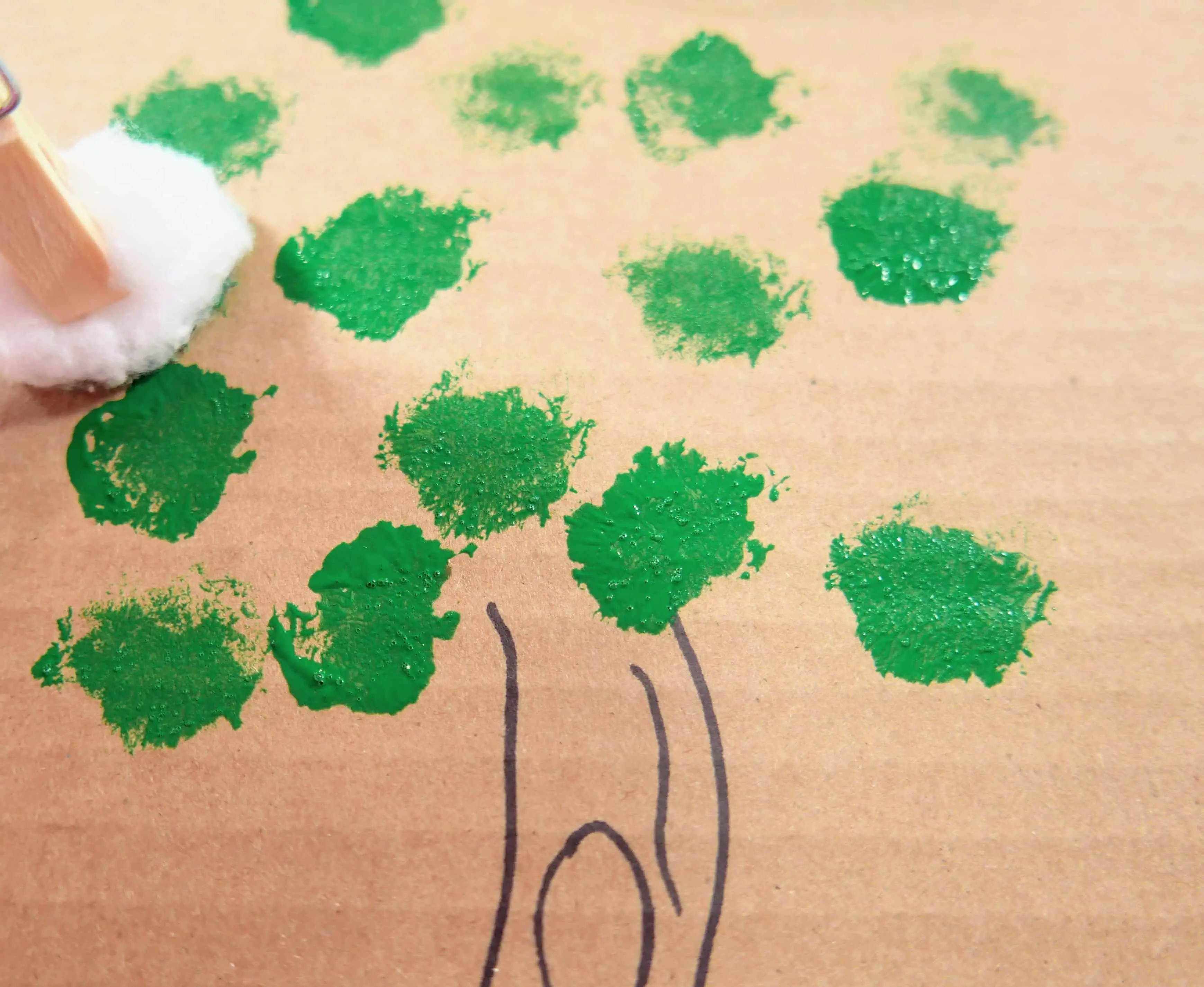 Holding a cotton ball with a clothespin and using it to dab different colors of paint for the summer leaves on our tree