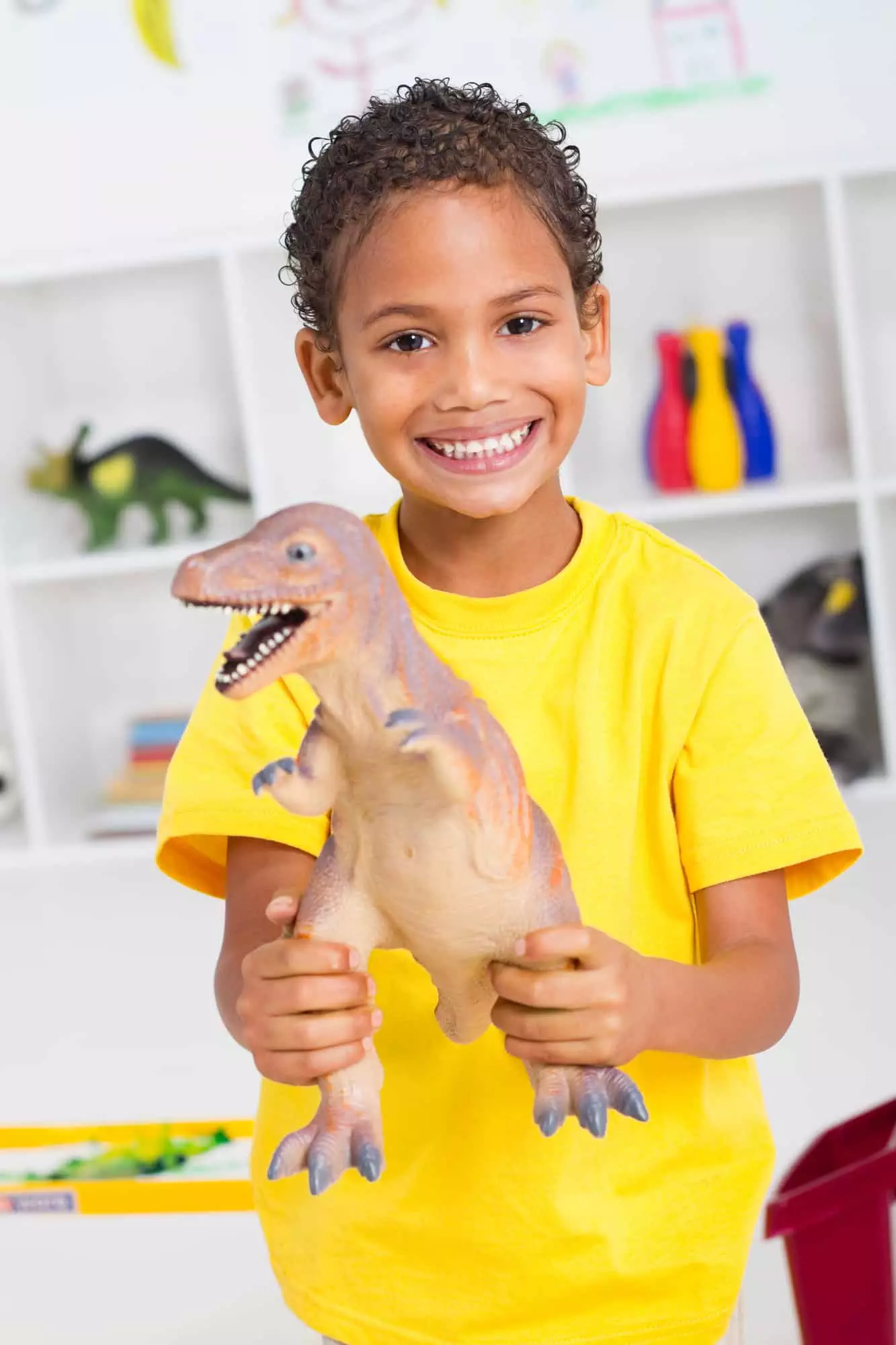 happy preschool boy playing with dinosaur toys for toddlers