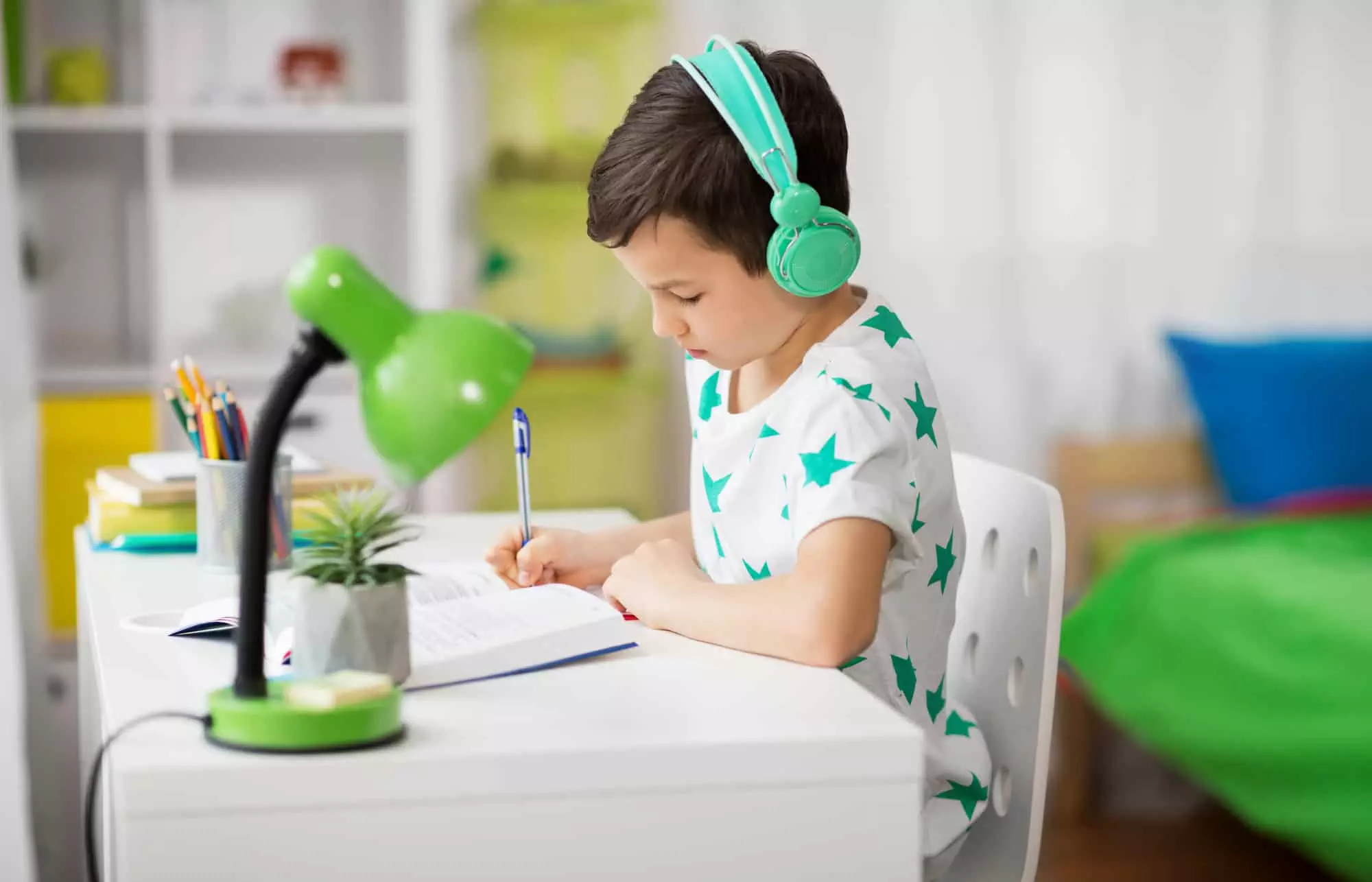 boy sitting at a desk doing schoolwork with headphones on