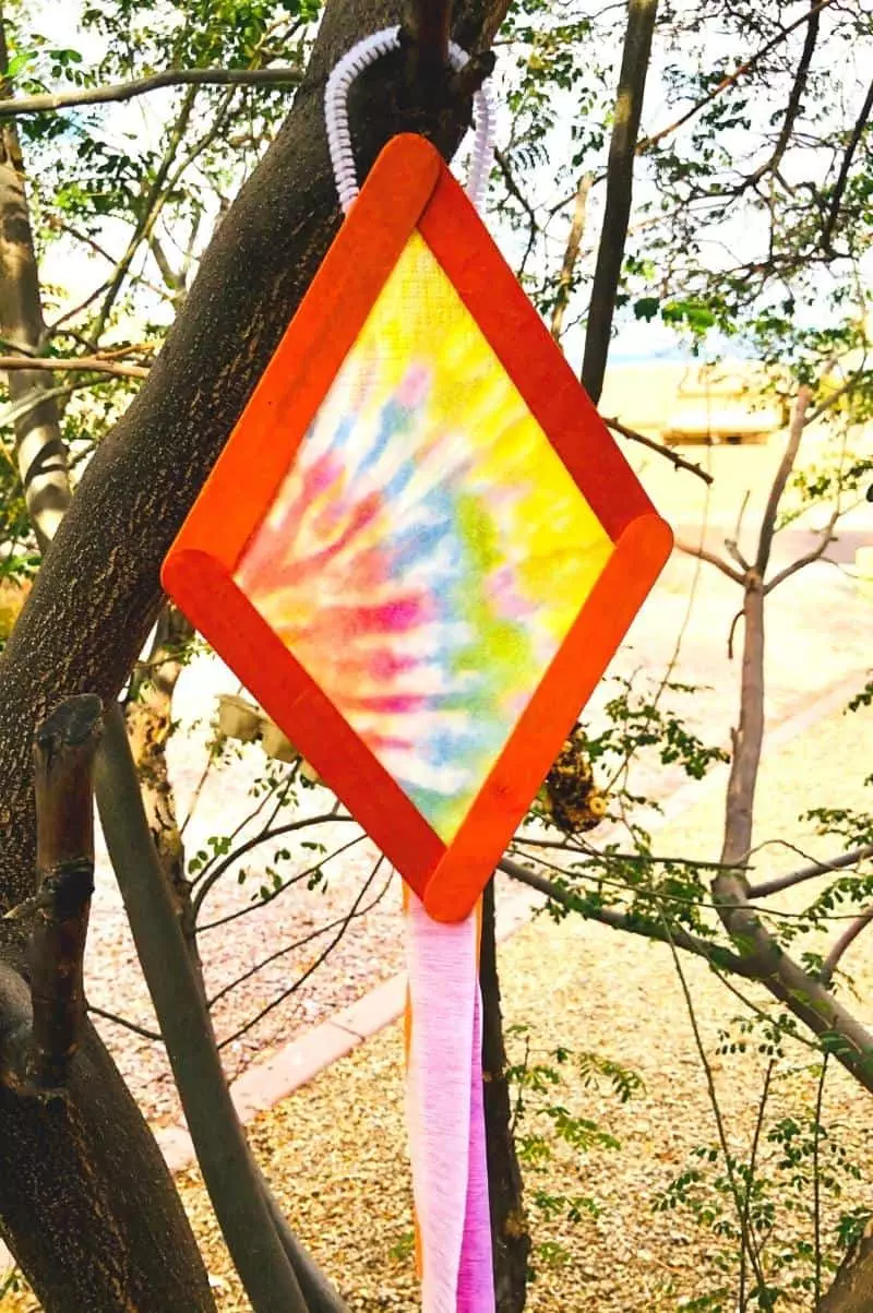 tie dye kite popsicle craft for kids hanging in a tree