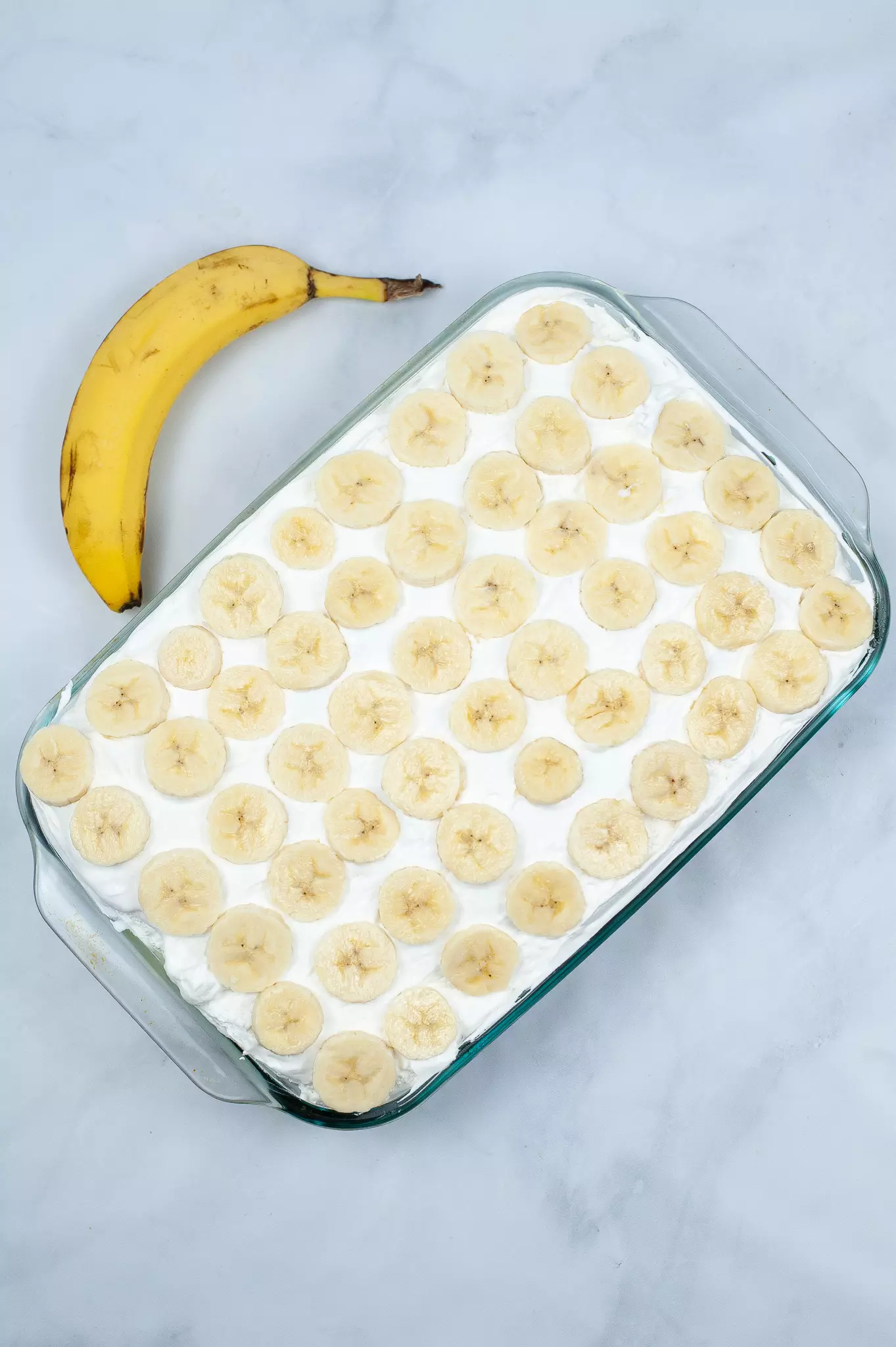 poke cake with whipped topping and sliced bananas on top