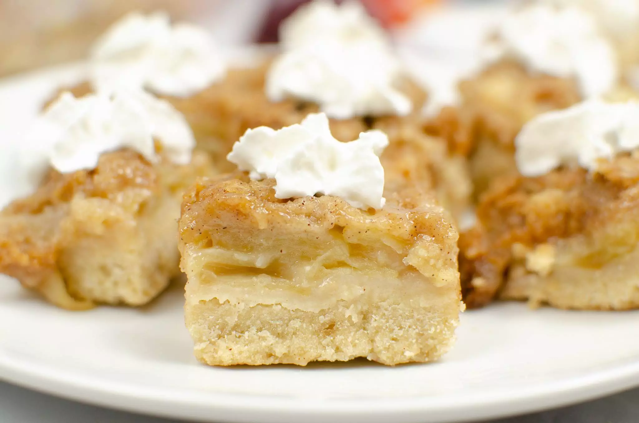 close up of apple crisp bars with whipped cream