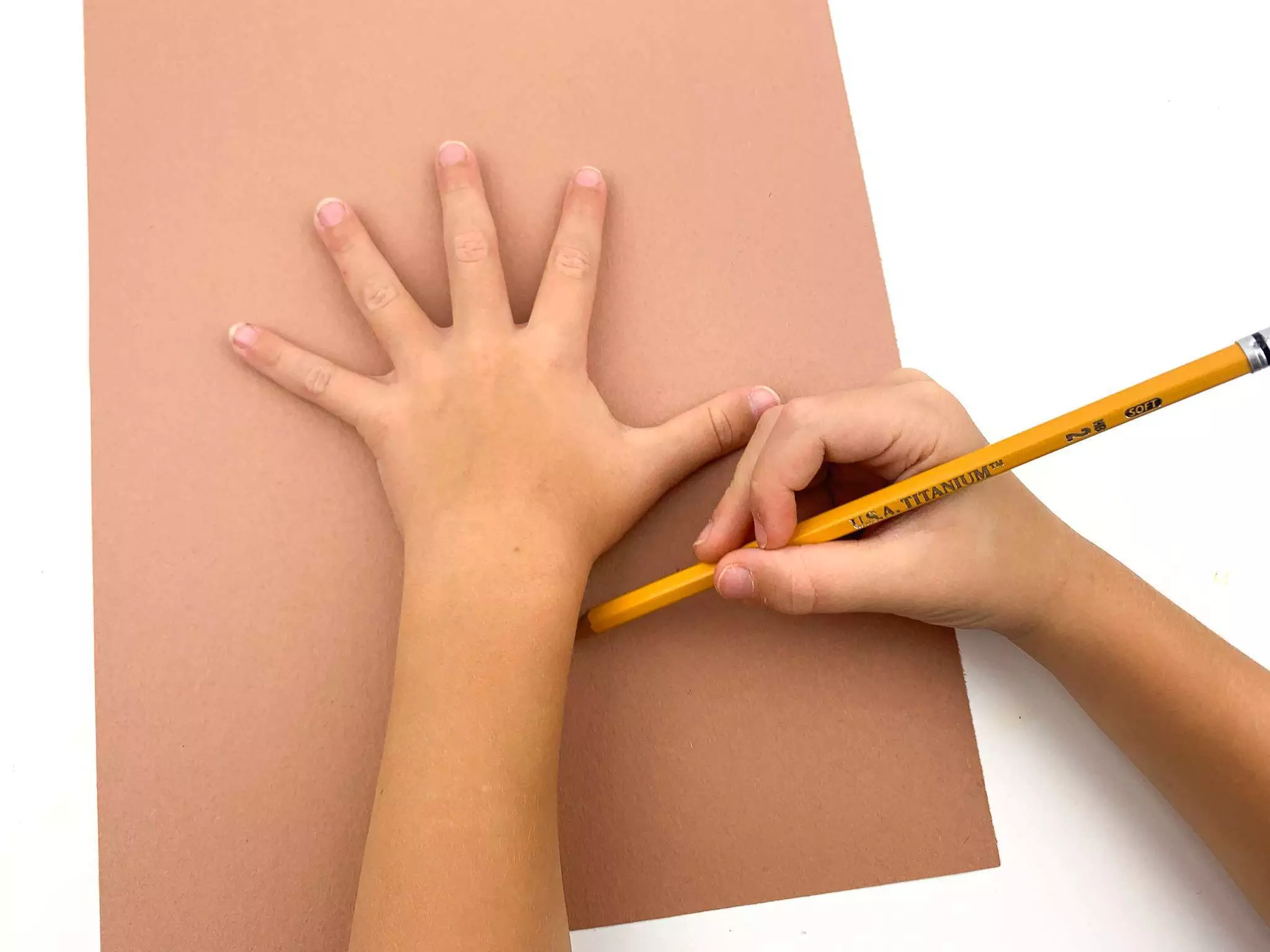 child tracing hand on construction paper