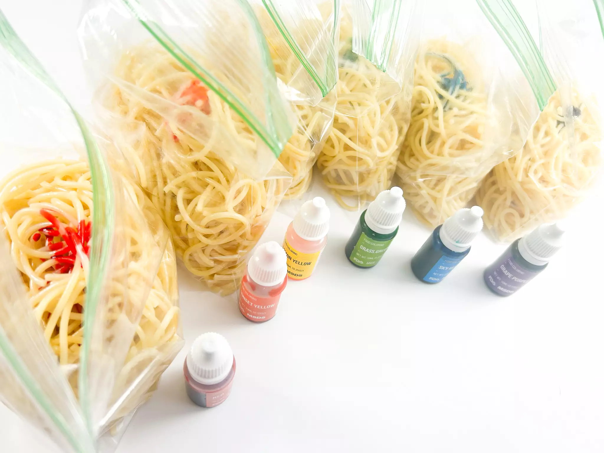 adding food coloring to bags of cooked noodles