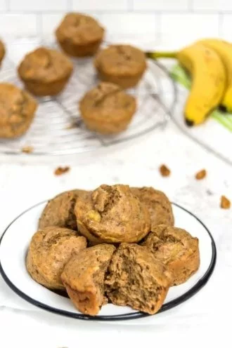 protein banana muffins on a plate with muffins and bananas in the background
